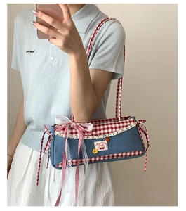 Detail of blue denim baguette bag with red gingham bows and white lace trim