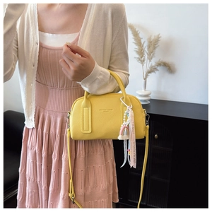 Detail of yellow lychee leather Boston bag with rainbow charm and pink love ribbon