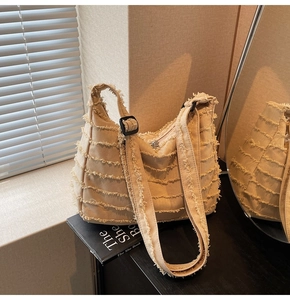 Close-up of beige canvas tote bag with textured tassel fringe and adjustable shoulder strap