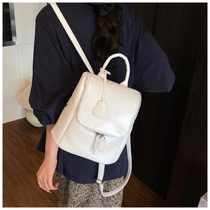 Side view of white minimalist faux leather backpack with adjustable straps and charm