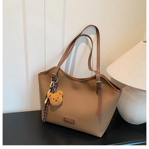 Detail of brown litchi pattern tote bag with teddy bear charm and metal buckle