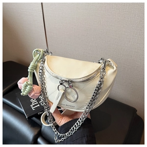 Detail of cream saddle bag with silver chain strap and colorful woven charm on a black seat
