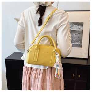 Close-up of a yellow pebbled leather Boston bag with a rainbow pendant and gold logo