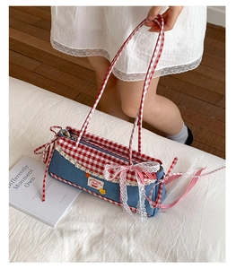 Detailed view of red and white checkered bow accents and lace trim on denim handbag