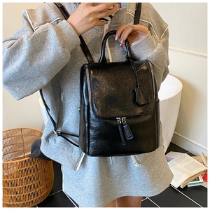 Detail of black glossy backpack featuring dual metal zippers and adjustable shoulder straps