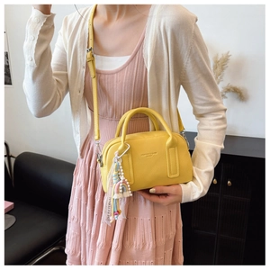 Detail of yellow lychee texture leather handbag with colorful rainbow charm and strap