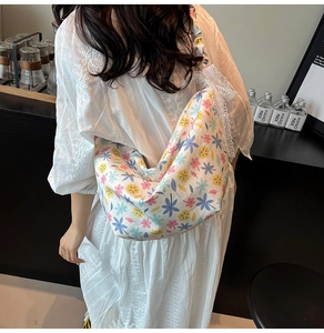 Close-up of hobo bag with colorful floral patterns and white lace pleated shoulder straps