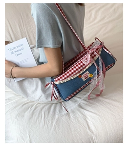 Detail of denim bag with red check trim, white lace edges and cherry patch accents