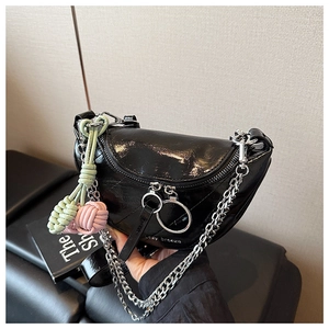 Detail of black patent leather saddle bag with quilted pattern and silver chain strap