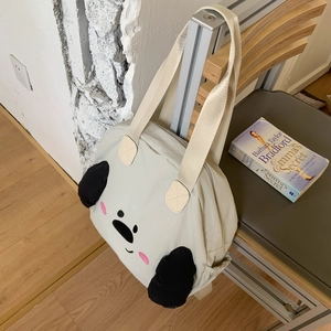 Detail of cream nylon tote bag with cute cartoon face and plush ears on a chair