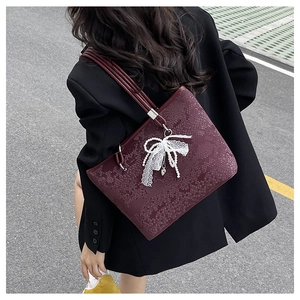 Burgundy snakeskin embossed tote bag with lace pearl bow charm on a street scene
