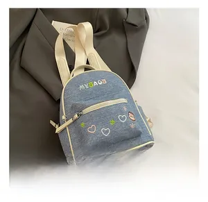 Detail view of mini denim backpack featuring cute heart and bear embroidery with MYBAGS logo