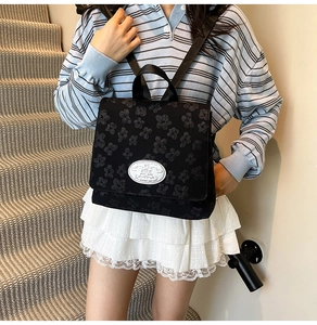 Detail eines schwarzen Nylon-Rucksacks mit 3D-Blumenprägung und ovalem Marken-Aufnäher