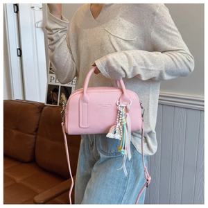 Detail of pink Boston bag with lychee texture and rainbow charm held by a model