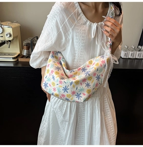 Floral print crescent bag with white lace trim shown in a cozy cafe setting