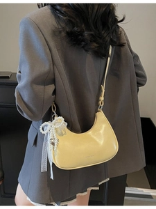 Hellgelbe glänzende Hobo-Tasche mit Perlenbogen und Herzanhänger an einem Model