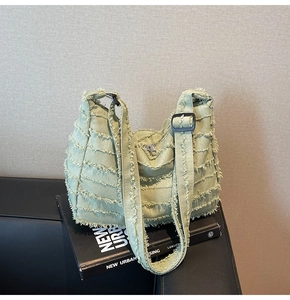 Detail view of sage green denim tote bag featuring raw edge layers and silver zipper close