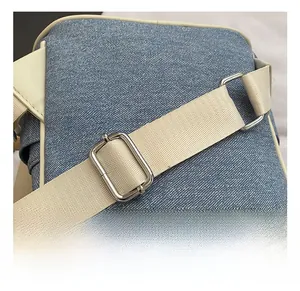 Detail showing the adjustable fabric strap and silver metal buckle on denim backpack