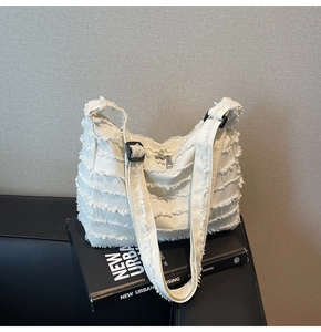 Detailed shot of white canvas tote featuring distressed frayed edges and adjustable strap