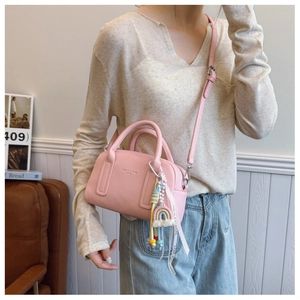 Pink lychee grain leather crossbody bag with rainbow charm and gold logo detail