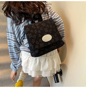 Detail eines schwarzen Kinderrucksacks mit Blumenstruktur auf einem Treppen-Hintergrund