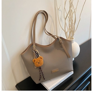 Detail of taupe tote bag with lychee grain texture and a cute brown bear charm