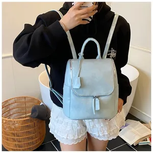 Lifestyle shot of light blue leather backpack with metal zipper and flap cover detail