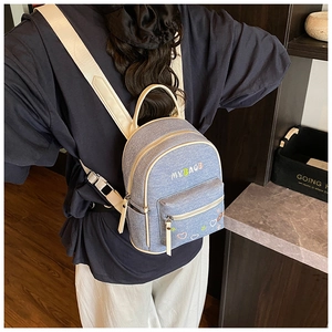 Detail showing the mini denim backpack in light blue with floral embroidery and white straps