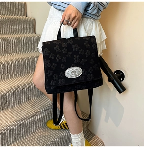 Detail des schwarzen Jacquard-Stoffs und der Silberplakette auf dem Mode-Rucksack