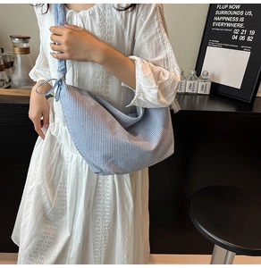 Detail of blue and white striped canvas crossbody bag with decorative bow knot shoulder strap