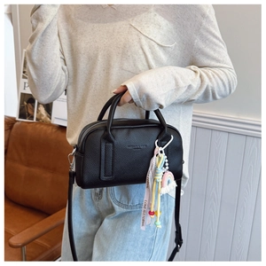 Detail of black pebbled leather Boston bag featuring a colorful rainbow tassel charm