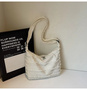 Detail shot of white canvas tote bag with fringed edges and textured striped fabric