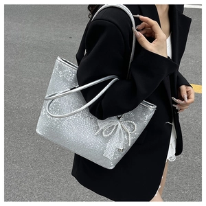 Close-up of silver snakeskin tote bag with white lace bow and elegant pearl charm detail