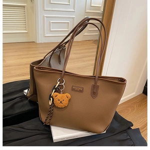 Dettaglio della borsa tote marrone che mostra la pelle martellata e la targhetta moda