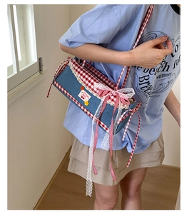 Detail of denim shoulder bag with red plaid bow, lace trim and cherry embroidery