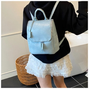 Light blue faux leather backpack with top handle and decorative zippers on model