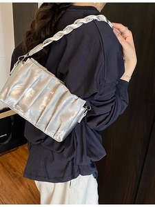 Chic silver pleated crossbody bag with a braided chain strap shown on a model