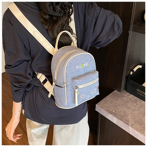 Detail of light blue denim backpack with MY BAG rainbow embroidery and white straps