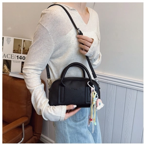 Detail of black pebbled leather Boston bag with rainbow charm and detachable strap