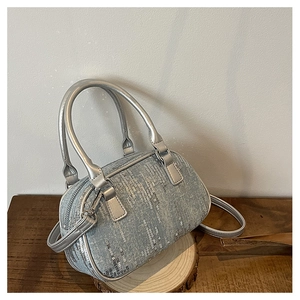 Detailed view of blue denim Boston bag featuring vertical silver sequins and metallic handles