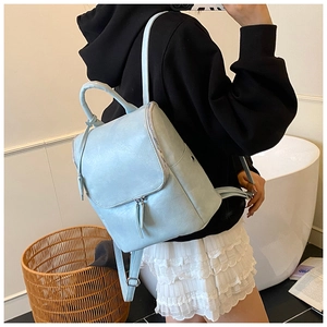 Rear view of a light blue faux leather backpack with adjustable straps on a female model