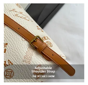 Detailed close-up of adjustable brown leather strap and bronze buckle on bucket bag