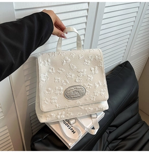 Weißer Rucksack mit geprägten Blumenmustern und einem silbernen Marken-Typenschild