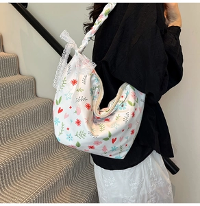 Detail of floral Oxford fabric bag with lace bow and secure metal zipper closure