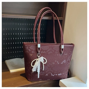 Detail of burgundy tote bag with faux snakeskin texture and pearl lace bow charm