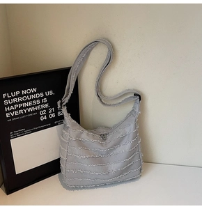 Detail of grey canvas tote bag featuring layered frayed edges and adjustable strap