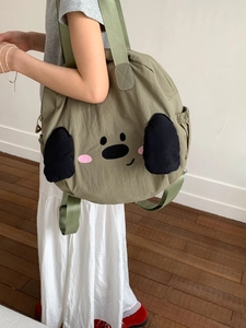 Green nylon shoulder bag with cute cartoon dog design shown on a person in daily life