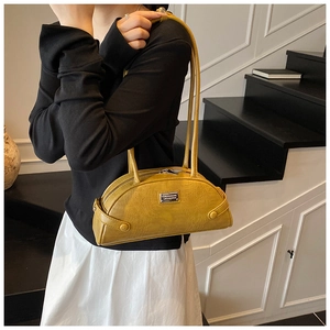 Detail of yellow crocodile pattern handbag with twin handles and metal logo plate