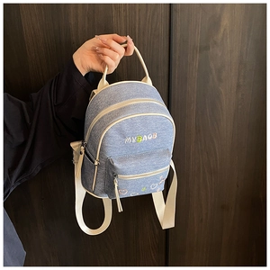 Detail of light blue denim backpack with MYBAOB embroidery and white contrast trim