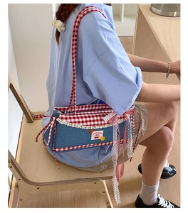 Close-up of sweet lace trim, cherry embroidery and red checkered bow on denim handbag